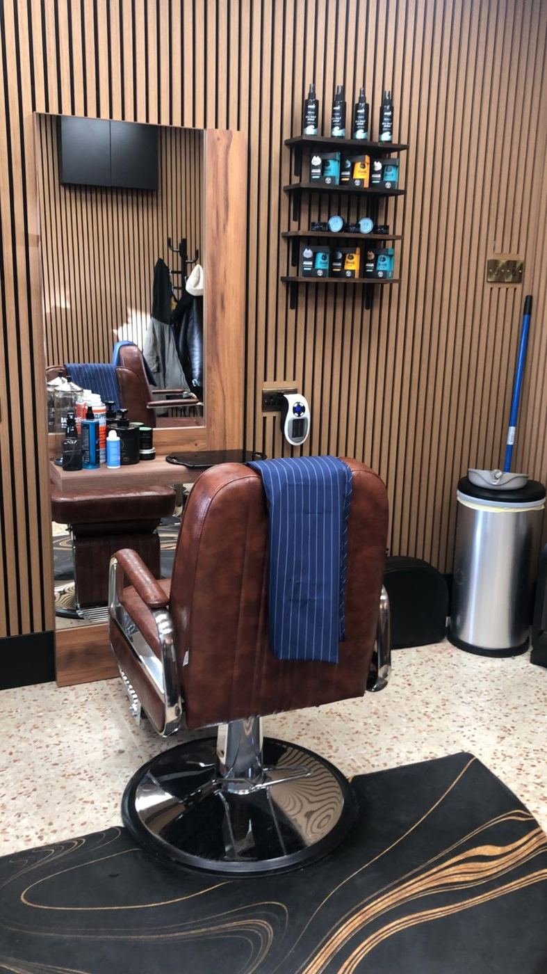 Brown leather barber chair in front of a timber-framed mirror